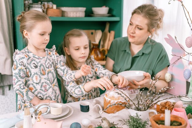 Zdjęcie Święta wielkanocne w sezonie wiosennym szczęśliwa rodzina szczere małe dzieci siostry dziewczyny razem matka bawi się w domu dekorowanie stołu na lunch lub kolację tradycyjne jedzenie świąteczny wystrój domu