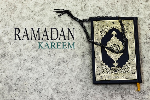 Święty Koran z arabską kaligrafią oznaczającą Al Quran i czarny różaniec