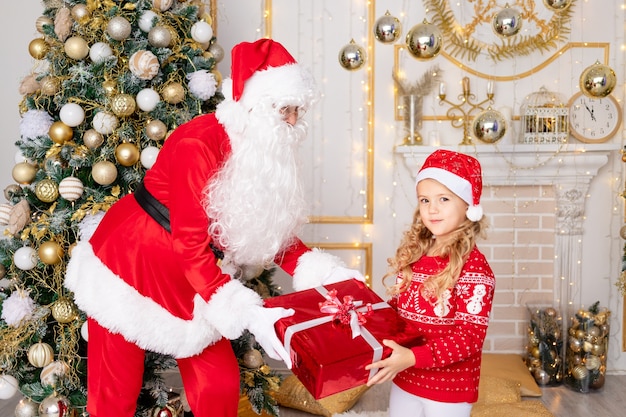Święty Mikołaj daje córeczce prezent na choinkę