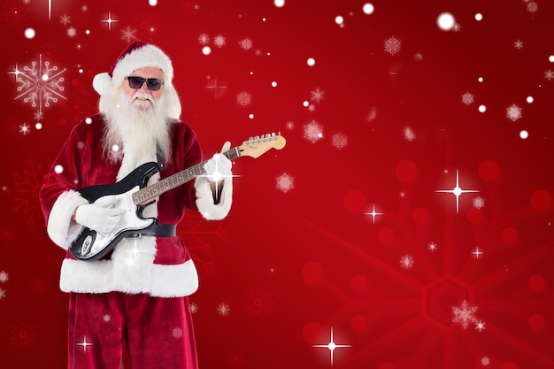 Święty Mikołaj gra na gitarze w okularach przeciwsłonecznych na tle czerwonego płatka śniegu