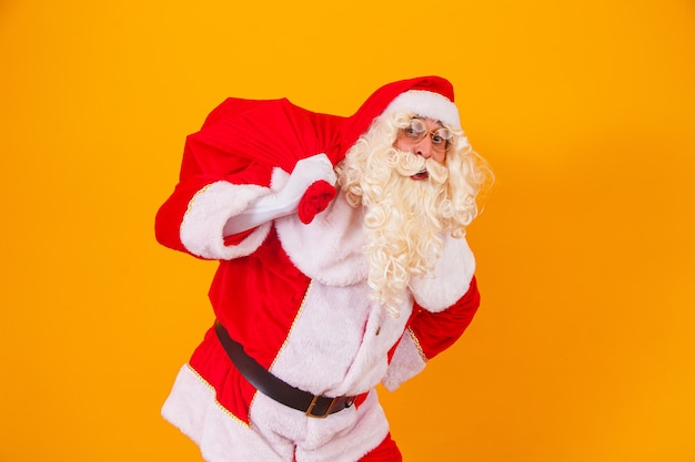 Święty Mikołaj Na żółtym Tle Trzymając Torbę Z Prezentami Za Jego Plecami. święty Mikołaj Robi Niespodziankę W Noc Bożego Narodzenia