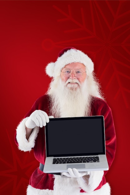 Święty Mikołaj przedstawia laptopa na czerwonym tle