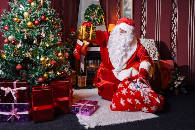 Święty Mikołaj siedzi obok choinki