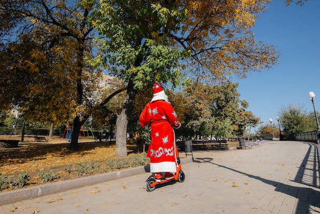 Święty Mikołaj spieszy się na skuterze z prezentami na święta dla dzieci.