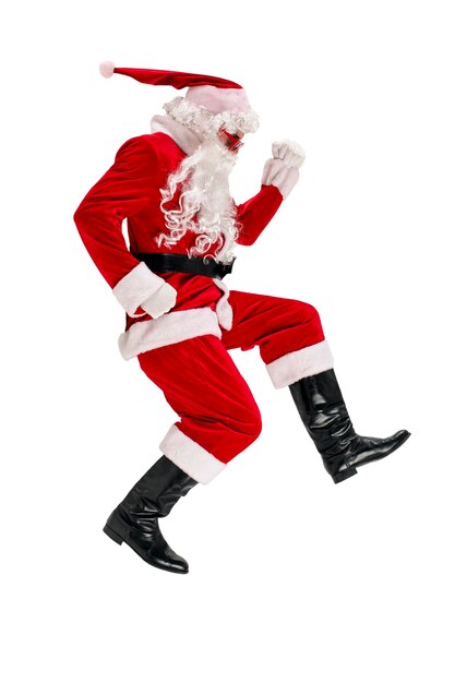 Święty Mikołaj w czerwonym garniturze z brodą w okularach biegnie szybko i spieszy się na białym, odizolowanym tle