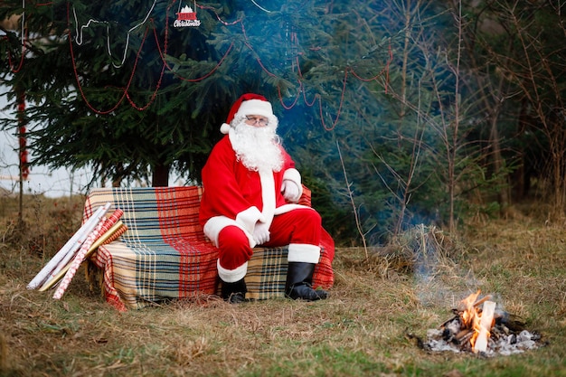Święty Mikołaj w czerwonym kostiumu z białą brodą Ozdobione choinki wokół zabawkami