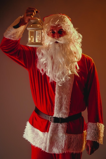 Święty Mikołaj z długą białą brodą trzyma świecznik z płonącą świecą