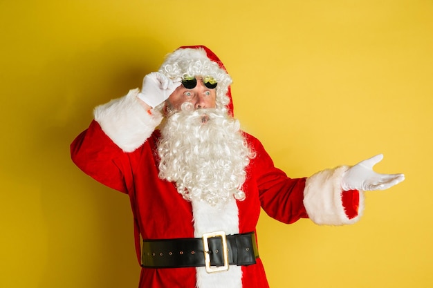 Święty Mikołaj z nowoczesnymi okularami na żółtym tle studyjnym