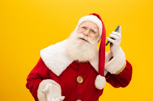 Święty Mikołaj Z Telefonem Komórkowym Na żółtym Tle