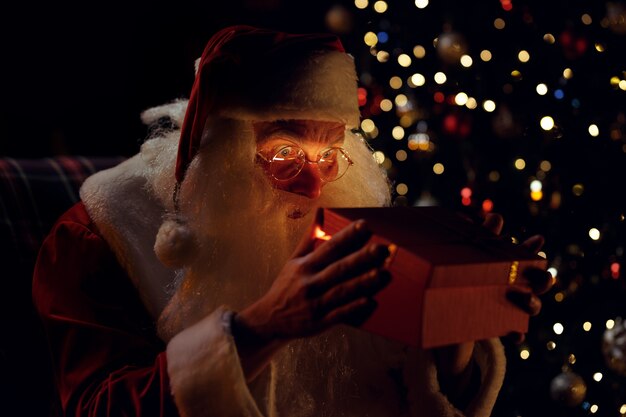 Święty Mikołaj zagląda do wnętrza prezentu i robi zdziwione spojrzenie