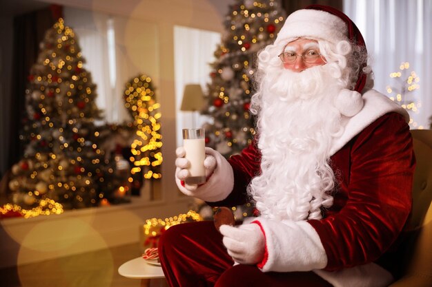 Święty Mikołaj ze szklanką mleka i ciasteczkami w pokoju urządzonym na Boże Narodzenie