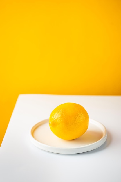 Świeża cytryna na talerzu na dwukolorowym tle żółtej i białej minimalistycznej kompozycji