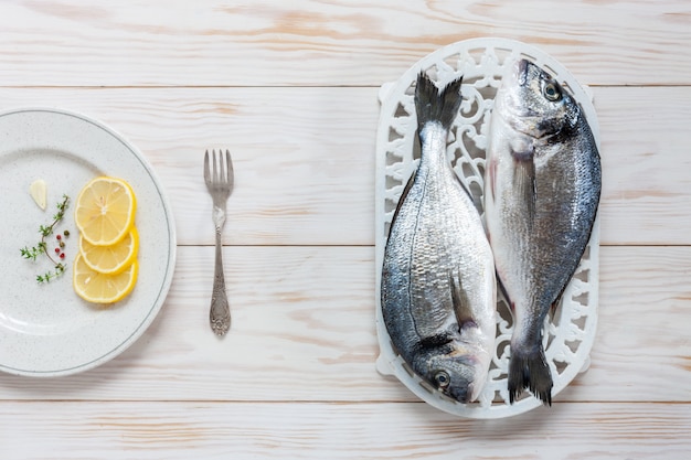Świeża dorado ryba z pikantność, oliwa z oliwek, czosnkiem i przyprawą na białym naczyniu na bielu stole.