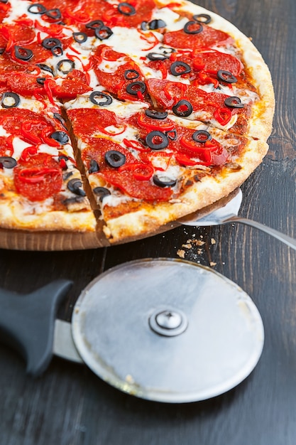 Świeża i pyszna włoska pizza na drewnianym stole i nóż do pizzy