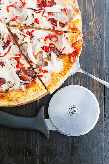 Świeża i pyszna włoska pizza na drewnianym stole i nóż do pizzy