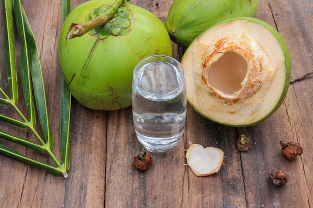 Świeża koks woda dla napoju w szkle z kokosowym liściem na drewnianym tle