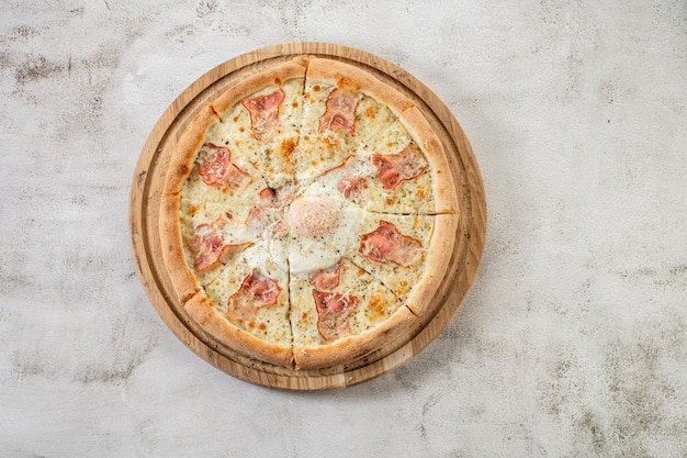 Świeża pizza carbonara z szynką i jajecznicą na betonowym tle