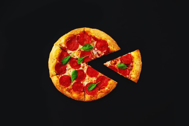 Świeża pizza pepperoni z odciętym kawałkiem na czarnym tlexA