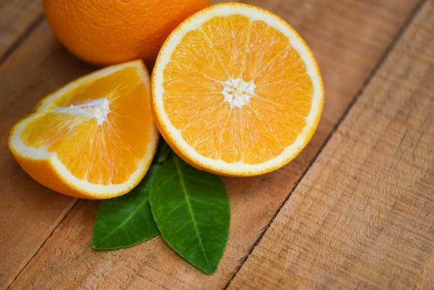 Świeża pomarańczowa plasterek połówka i pomarańczowego liścia owoc żniwa zdrowe pojęcie - Pomarańczowa owoc na drewnianym