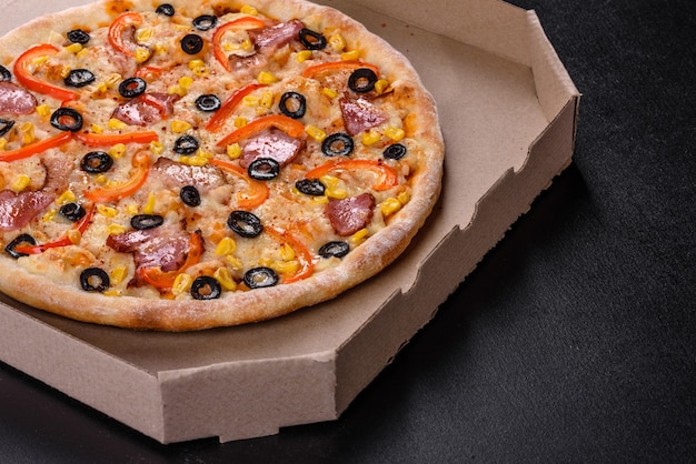 Świeża pyszna pizza pieczona w piecu paleniskowym z oliwkami, papryczką chili i szynką