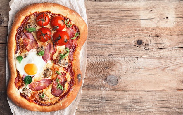 Świeża pyszna pizza z pieca z jajkiem, prosciutto i pomidorem