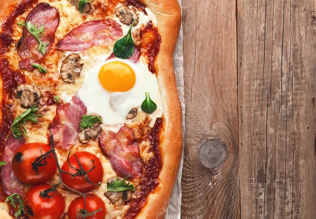 Świeża pyszna pizza z pieca z jajkiem, prosciutto i pomidorem