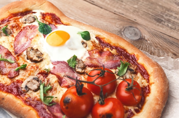 Świeża pyszna pizza z pieca z jajkiem, prosciutto i pomidorem