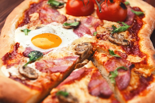 Świeża pyszna pizza z pieca z jajkiem, prosciutto i pomidorem