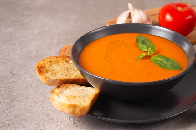 Świeża zdrowa zupa pomidorowa z pomidorami czosnkowymi z papryką bazyliową i chlebem na drewnianym tle