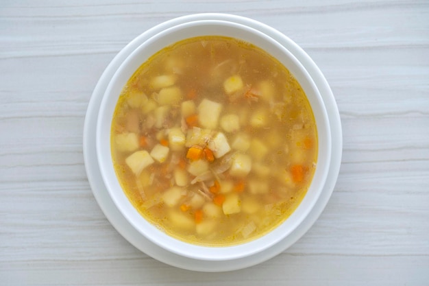 Zdjęcie Świeża zupa rybna z marchewką, ziemniakami i cebulą w białym talerzu z bliska smaczny obiad składa się z zupy rybnej z tuńczykiem
