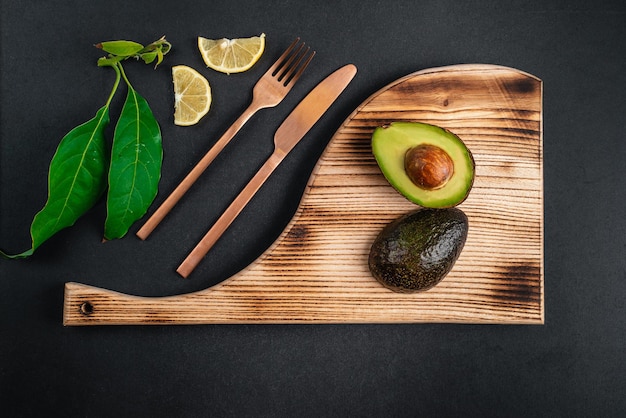 Świeże awokado leży na drewnianym talerzu na czarnym tle Zdrowa żywność
