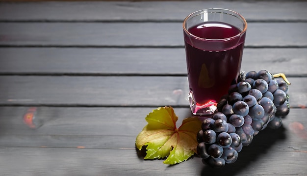 Zdjęcie Świeże czarne winogrona z liśćmi i szklanka soku na drewnianym stole