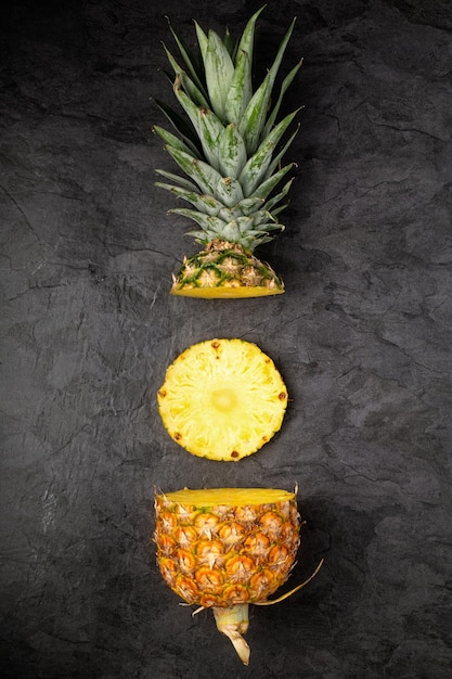 Świeże, dojrzałe przekróje ananasu na ciemnym tle w kompozycji pionowej