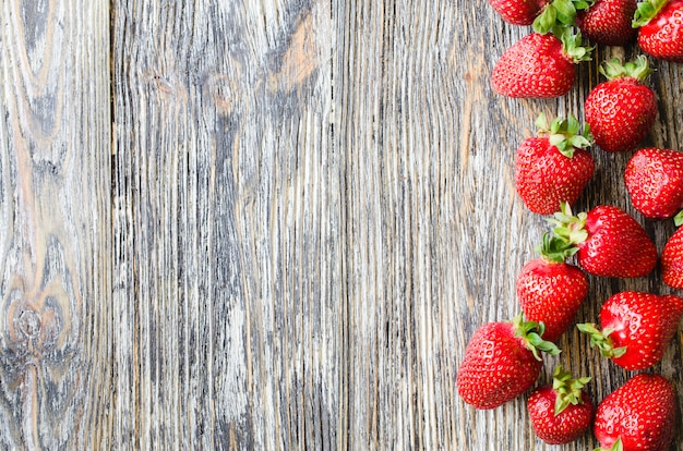 Świeże dojrzałe truskawki na drewnianym tle. Organiczne soczyste jagody.