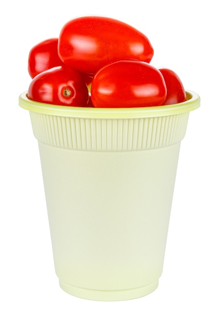 Świeże i dojrzałe czerwone pomidorki koktajlowe w zielonym jednorazowym kubku na białym tle