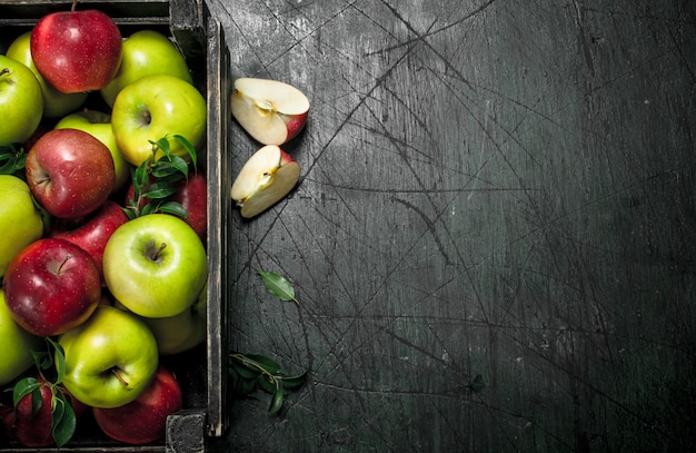 Świeże jabłka z liśćmi w pudełku na rustykalnym stole.