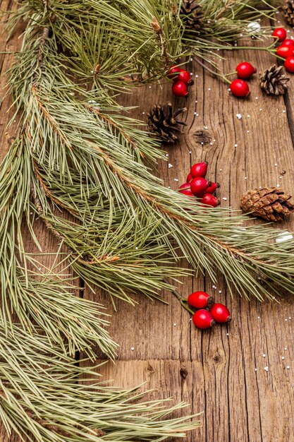 Świeże jagody róży, cukierki kulkowe, gałęzie i szyszki sosny, sztuczny śnieg. Dekoracje przyrodnicze, zabytkowe drewniane deski