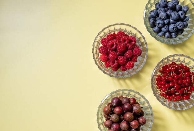 Świeże letnie jagody w szklanych miskach na kolorowym tle z cieniami zdrowego stylu życia dieta