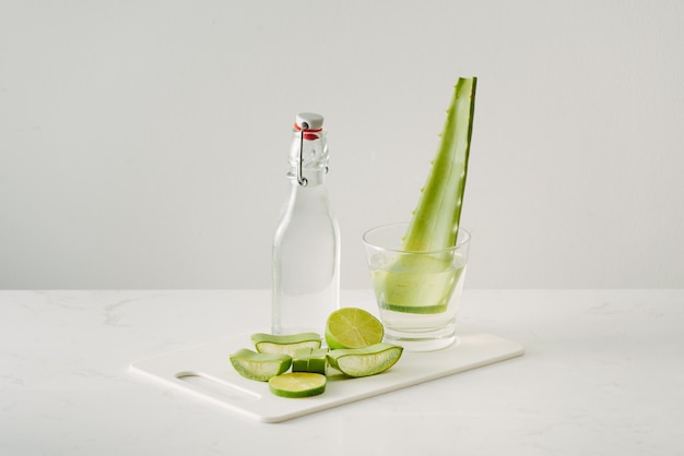 Świeże liście aloesu i sok z aloesu w szklanej butelce na białym tle