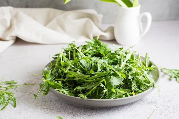 Świeże liście rukoli na talerzu na stole. Dieta organiczna wegetariańska. Styl życia