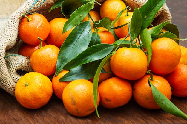 Świeże mandarynek pomarańcze owocowe z liśćmi na drewnianym stole