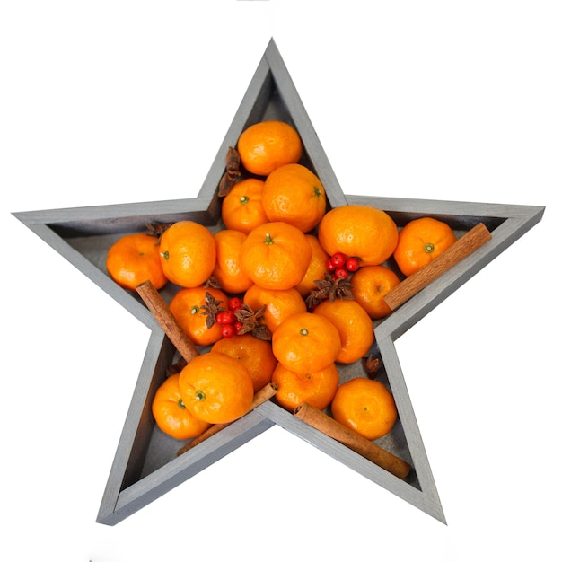 Świeże mandarynki z czerwonymi jagodami w pudełku w kształcie gwiazdy na białym tle.