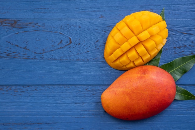 Świeże mango - piękny posiekany owoc z zielonymi liśćmi. Koncepcja projektowania owoców tropikalnych. Leżał na płasko. Widok z góry.