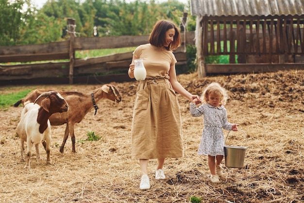 Świeże Naturalne Mleko Młoda Matka Z Córką Jest W Lecie Na Farmie Z Kozami