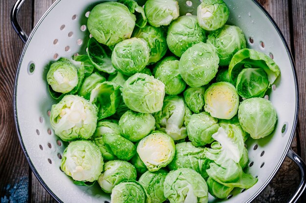 Świeże organiczne brukselki w durszlaku na drewnianym stole