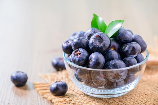 Świeże organiczne jagody w szklanej misce na drewnianym tle widok z boku Zdrowe owoce