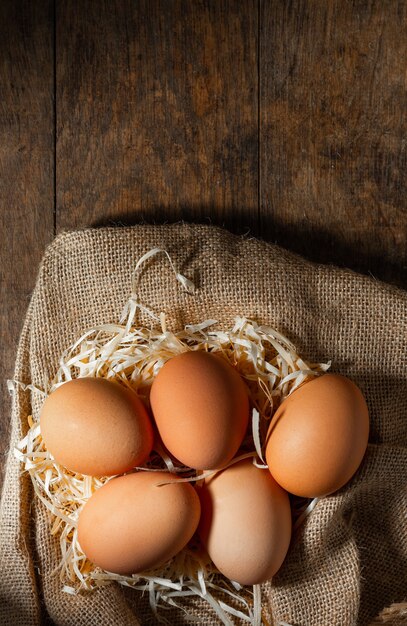 Świeże organiczne jajka w płótnie z suchej trawy na stół z drewna.