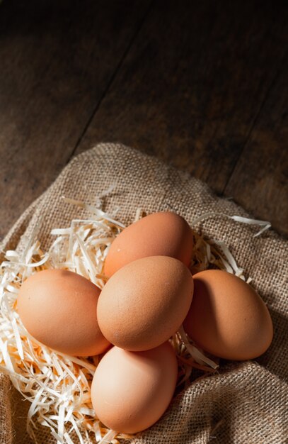 Świeże organiczne jajka w płótnie z suchej trawy na stół z drewna.