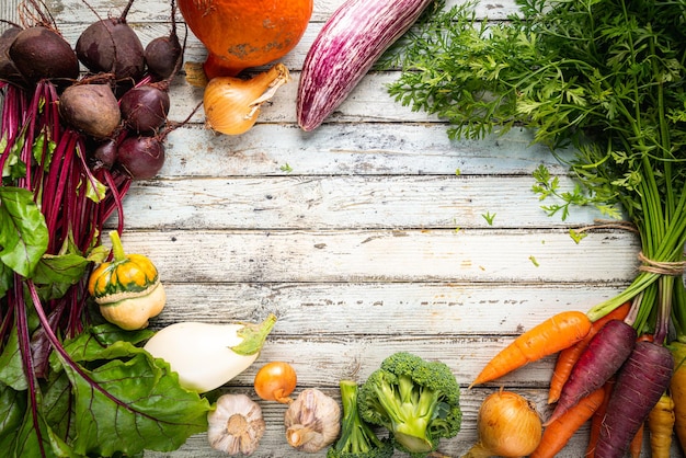 Świeże organiczne marchewki i buraki z liśćmi warzyw korzeniowych na drewnianym tle widok z góry