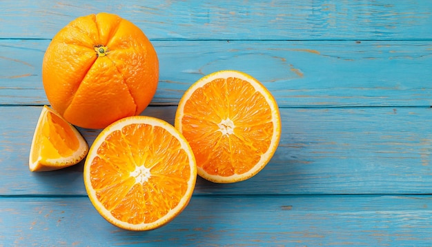Świeże organiczne pomarańcze na pół owoców na niebieskim drewnianym tle z przestrzenią kopiowania
